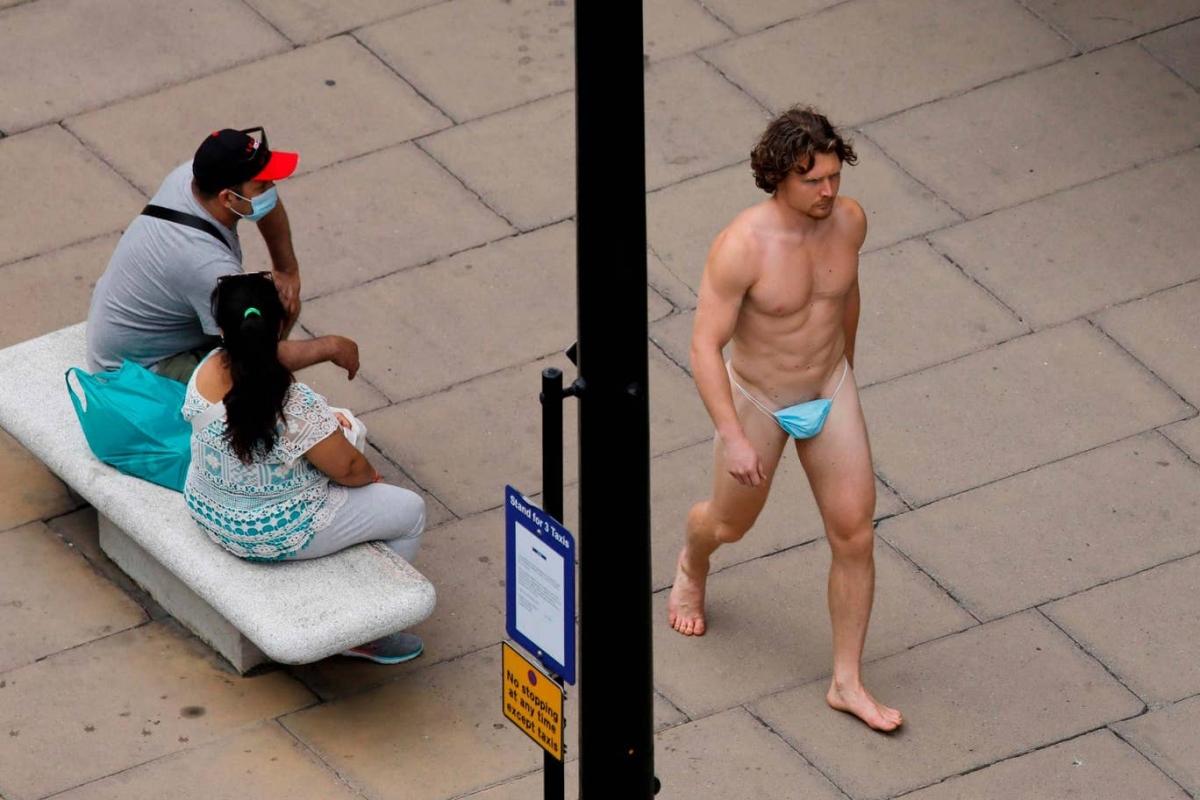 A man wearing a surgical mask as G-string walks past a woman, as the spread of the coronavirus disease (COVID-19) continues, on Oxford Street in London, Britain July 24, 2020. REUTERS/Simon Dawson