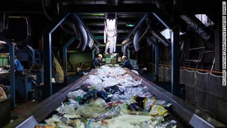 Workers sort disposable plastic waste on a conveyor at Ichikawa Kankyo Engineering recycle center. Tokyo&#39;s Katsushika city office brings some 10 tons of plastic recyclable resources to the recycling facility daily.