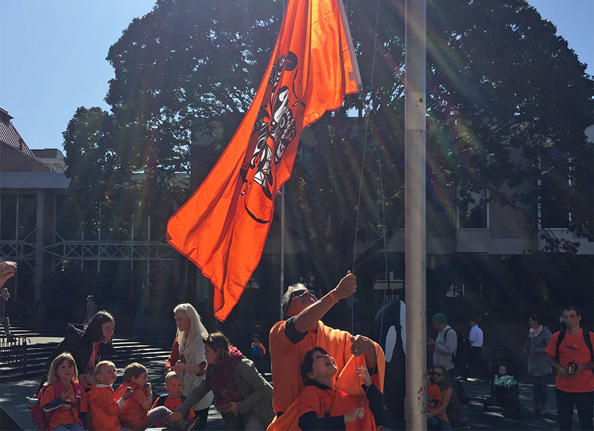 Haley and her dad raise a massive orange flag triumphantly up a flagpole.