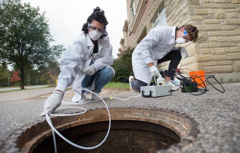 University of Guelph engineering students Melissa Novacefski, left, and Jonathan Evans, pump wastewater from a sewer outside a student residence on campus in late September to test for traces of COVID-19 RNA. Similar studies are being conducted in other cities, including Toronto.