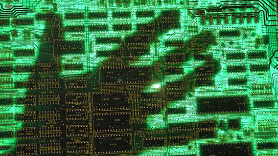 The shadow of a hand hovers over a computer circuit board © Picture-Aliken / Joker Photo: Alexander Stein