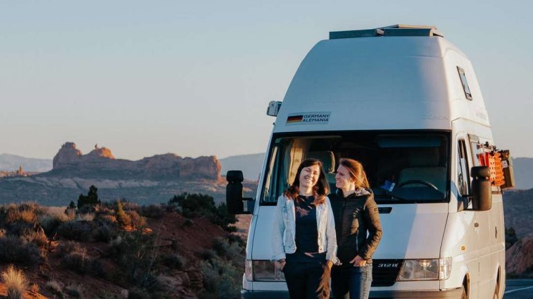 The day's last rays of sunshine turn the landscape red in Arches National Park: Anne Hopfengartner (left) and Anna Schmelzer stand in front of their van.